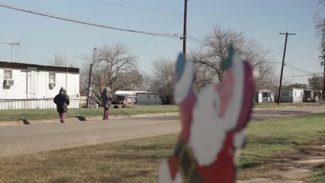 niños caminando por la calle detrás de la decoración navideña de santa