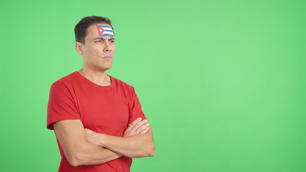 Man with cuban flag painted looking away with serious expression