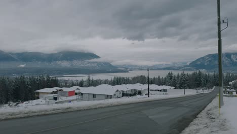 Toma-Panorámica-De-Casas-Residenciales-En-Invierno-Con-Montañas-Y-Lago.