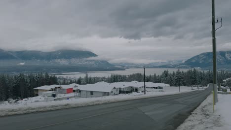 panning shot of residential houses in winter with mountains and lake
