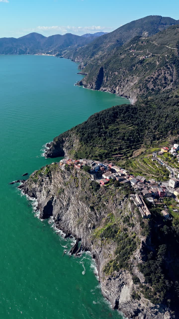 Veduta costiera di Corniglia, che mostra scogliere, colline verdi e acqua turchese.