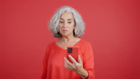 Smiling Senior Woman Using a Red Phone