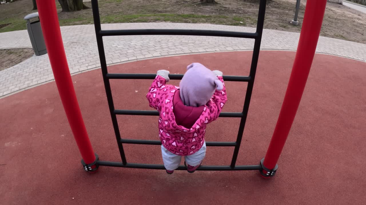 Little Girl Climbing On The Ladder In The Playground. - high angle shot
