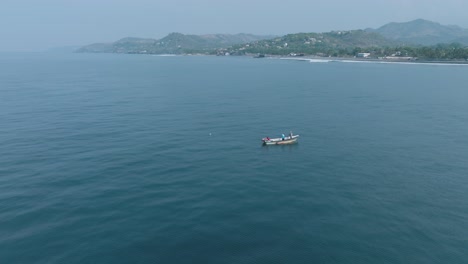 panorámica aérea en cámara lenta vista de un pequeño barco de pesca en el tunco el salvador