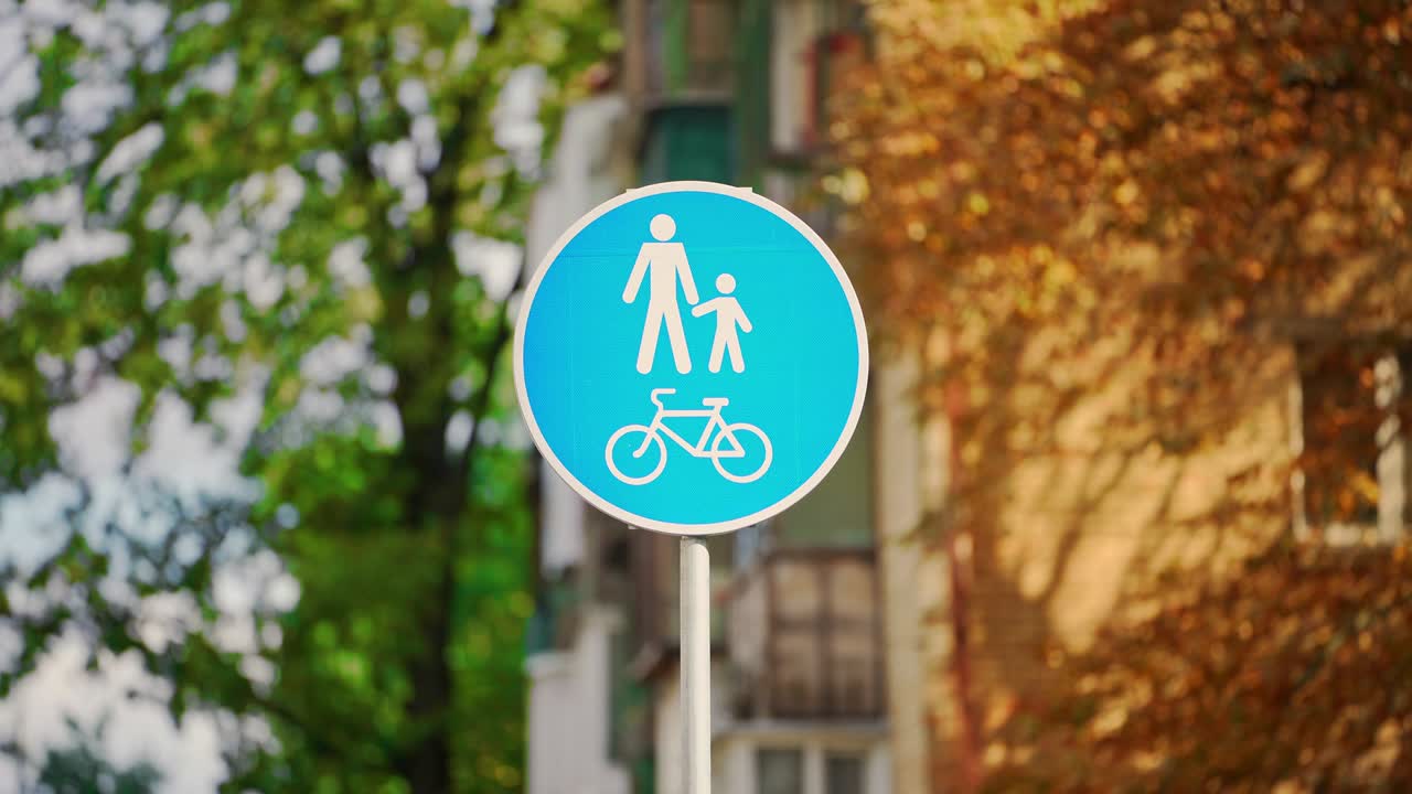 오렌지색과 초록색의 나무를 배경으로 한 파란색 표지판, 가을 공원, 자전거 표지판.