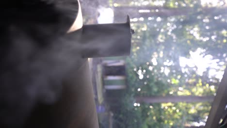 smoke billows out of a backyard smoking barbque grill, vertical orientation