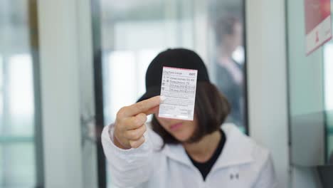 woman hold public transport ticket in extended hand in front of face, denmark