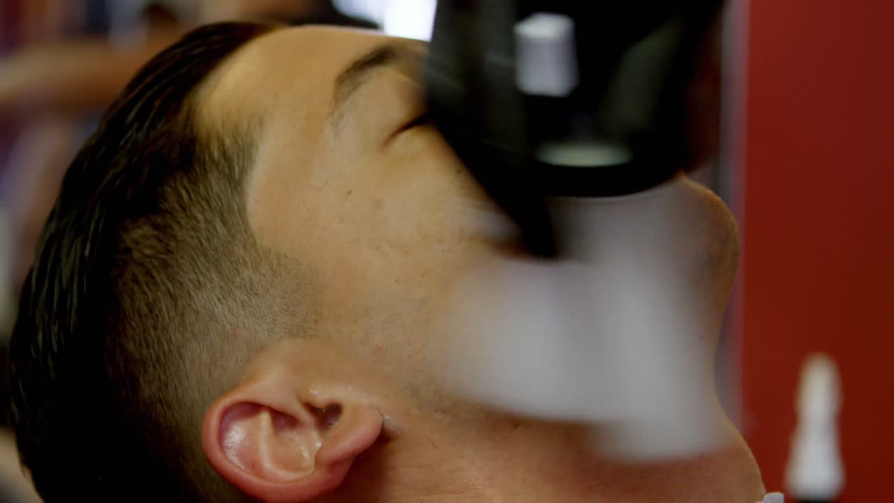 barbero limpiando la cara del cliente con un pincel 4k