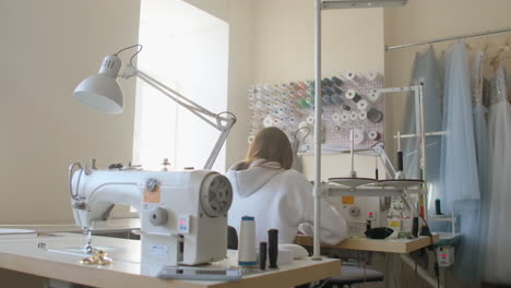 taller de costura una mujer está trabajando en la costura de ropa usando una máquina de cuello. la vista desde la parte de atrás.