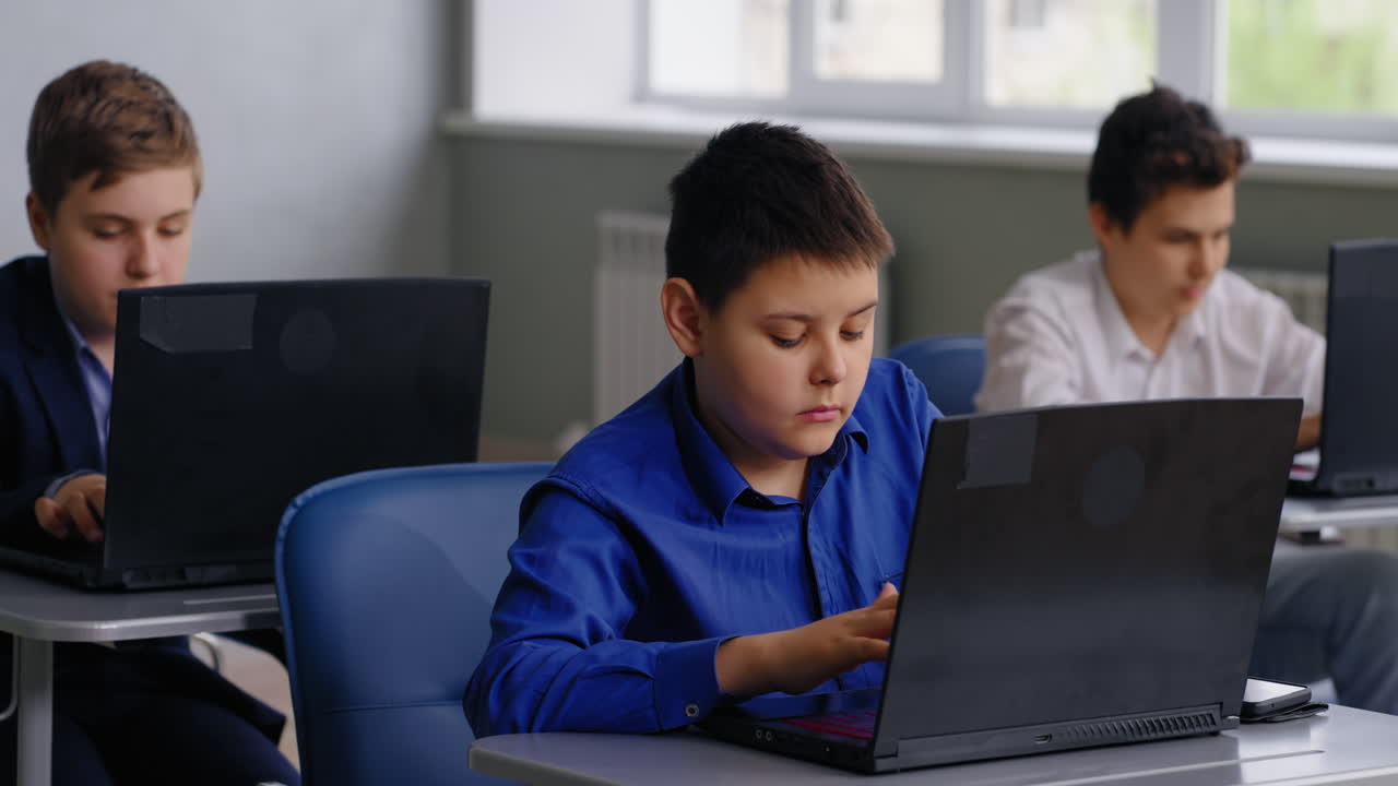 estudiantes trabajando en computadoras portátiles en un aula