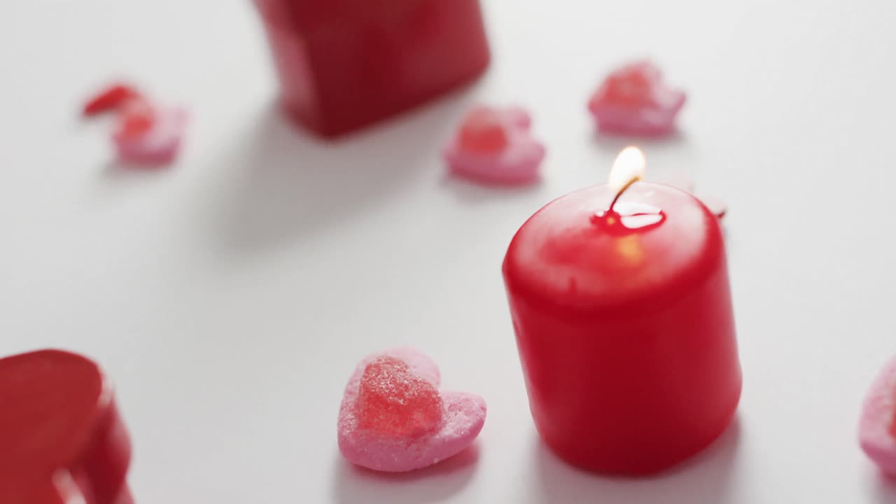 Heart shape sweets and candles on pink background at valentine's day