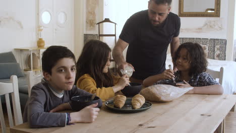 Cheerful-father-pouring-milk-into-kids-plates.