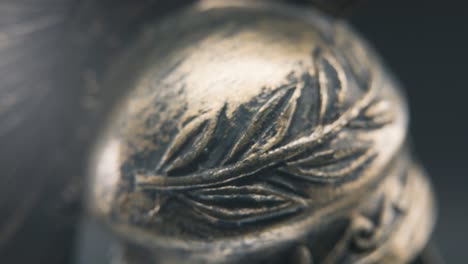 a dynamic close up macro slow tilt down shot of a spartan face design, warrior ancient greek bronze helmet, on a 360 rotating stand, studio lighting, depth of field, 4k smooth movement