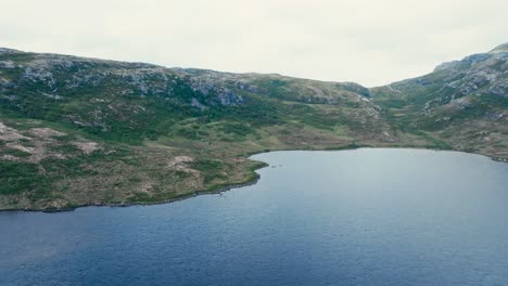 una vista cautivadora de las aguas serenas del lago pålvatnet, rodeado de escarpadas colinas en åfjord, condado de trøndelag, noruega - avión no tripulado volando hacia adelante