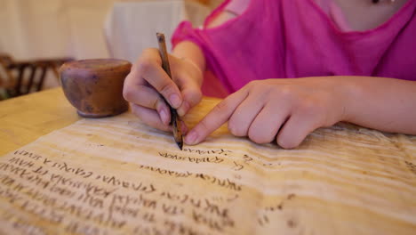 a handheld push-in shot focuses on a woman in historical costume writing on parchment with a quill pen. the camera moves closer to the nib as she practices ancient calligraphy