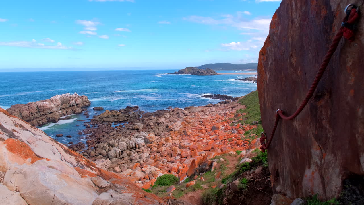 Cordas-guia montadas na lateral de uma grande rocha na trilha da Reserva Natural Robberg.