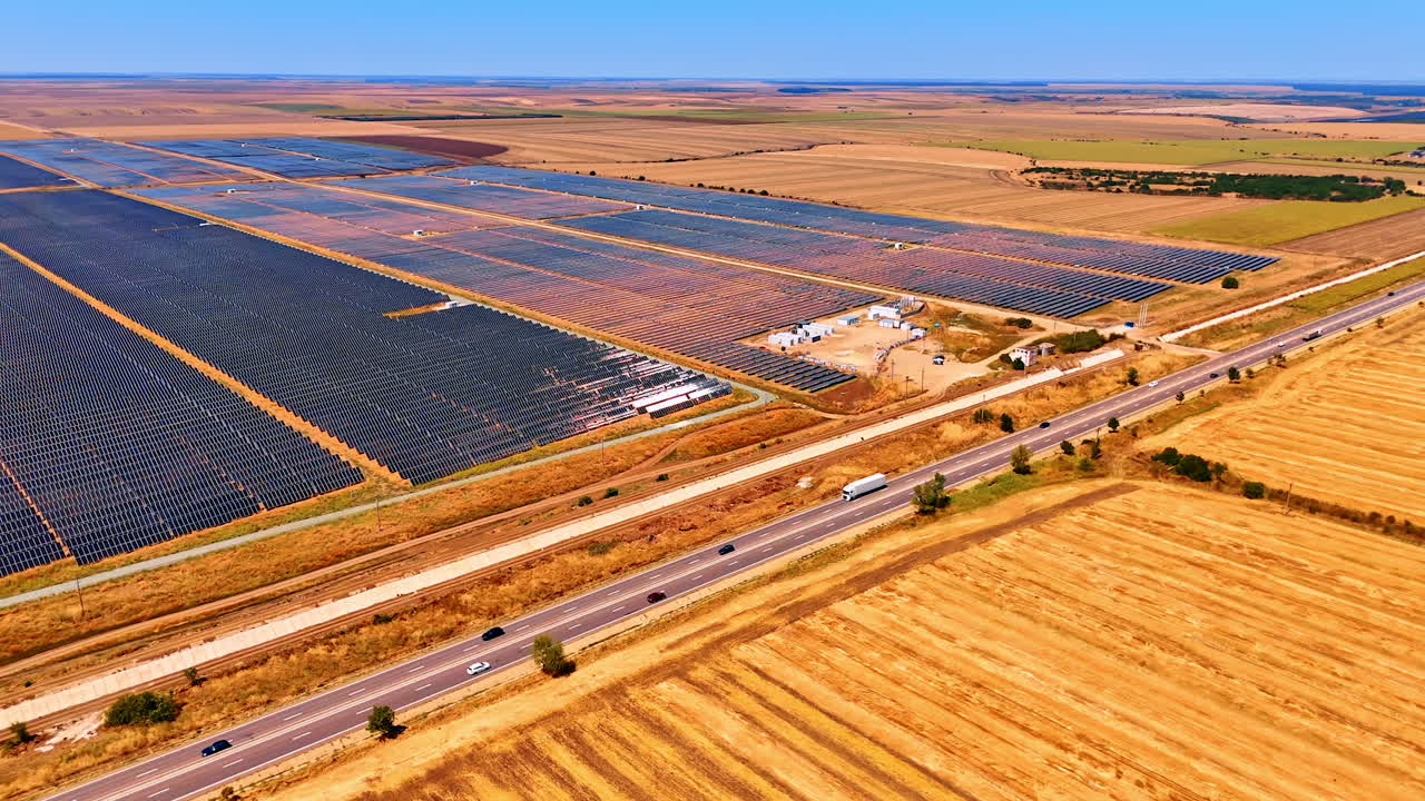 Cars move quickly by the highways along the vast fields in the countryside. Aerial perspective on the site with solar panels