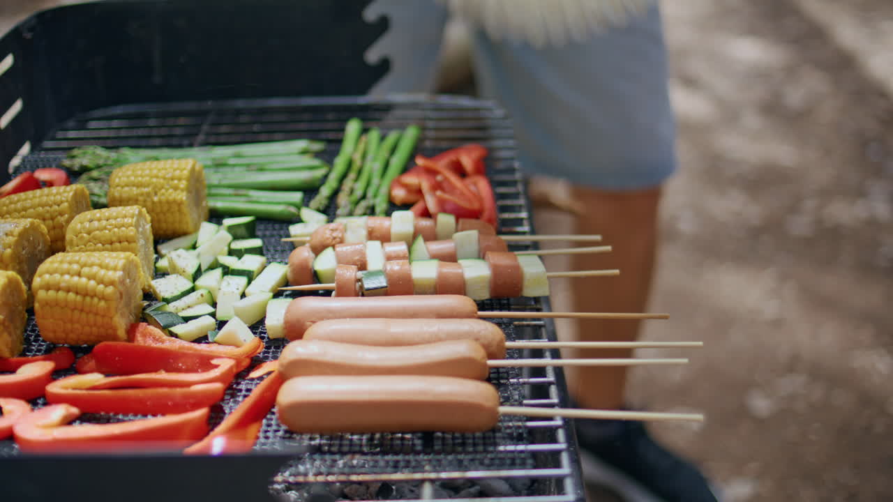 Grill filled fresh vegetables and sausages at sunny forest barbecue closeup