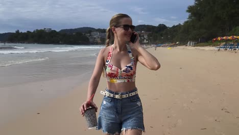 una mujer en la playa hablando por teléfono.