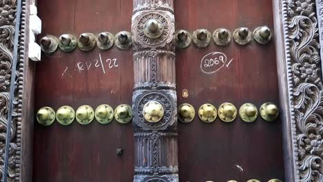 Tilt-down-revealing-an-Indian-door-in-Zanzibar-with-numbers-written-in-chalk-located-in-Stone-Town-old-town-neighbourhood