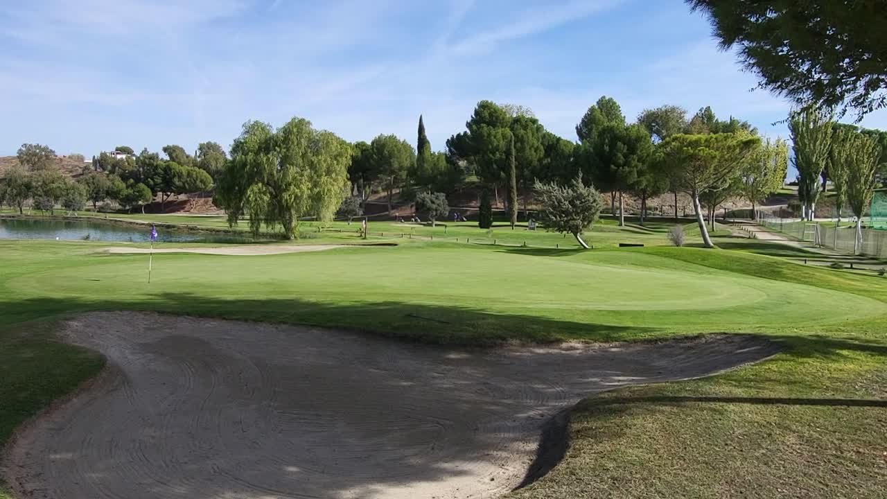 Campo da golf. Green, bunker, lago e golfisti in una giornata di sole. Veduta panoramica di un campo da golf. Campo da golf spagnolo. Spagna.