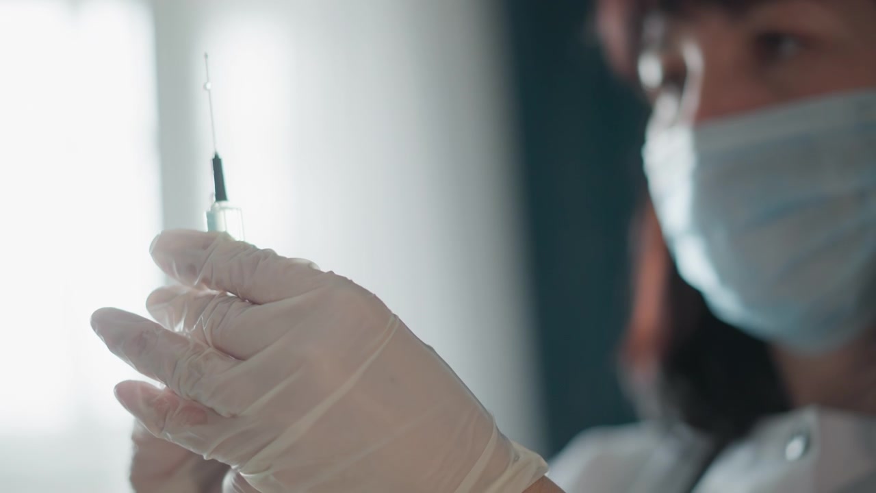Healthcare worker carefully measuring medication with syringe in clinical setting. Steady hands of nurse accurately drawing medication into syringe through backlit window in medical environment