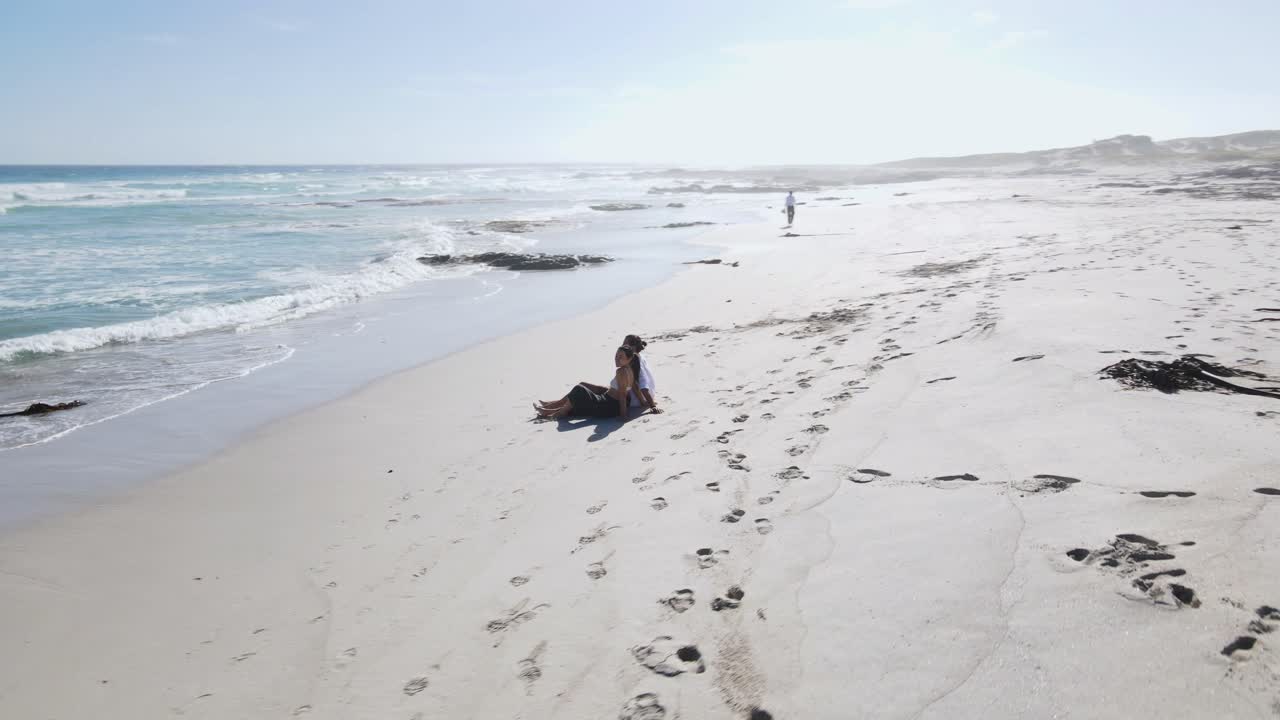 해변에 앉아 남아프리카 해변의 하얀 모래 위에서 서로 키스하는 로맨틱한 커플 - 공중 원 샷