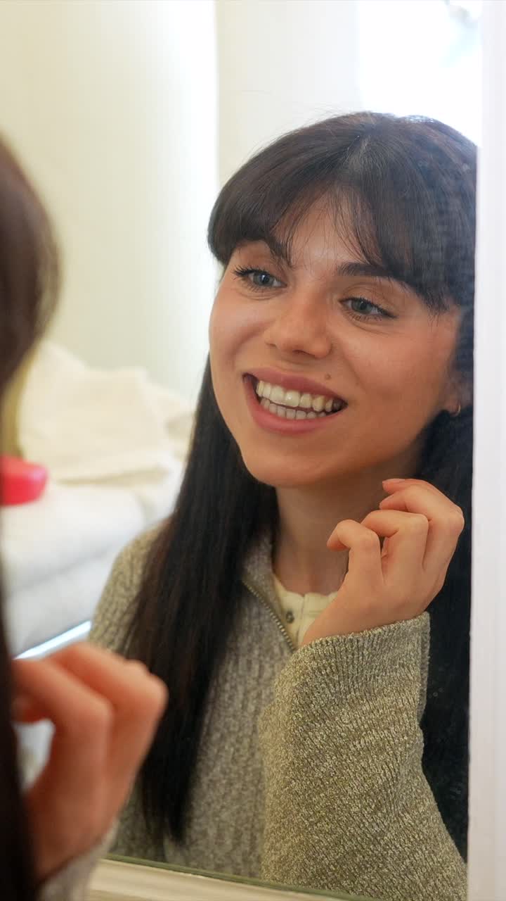 Mujer joven poniéndose y quitándose un alineador dental transparente frente al espejo