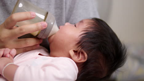 sucking some milk from a feeding held by her mother, a newborn child cries as her mom pulls away the baby bottle from the bay's mouth