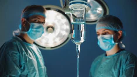 medical professionals in a surgical operating room with iv drip