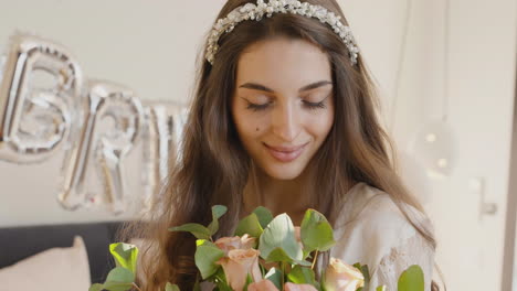 novia sosteniendo ramo con banda para el cabello con flores, mirando a la cámara mientras sonríe