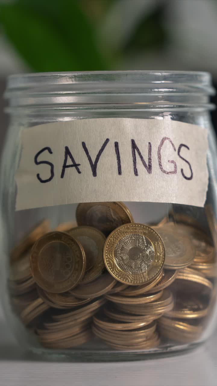Time-lapse Saving Money Concept. Coins into Glass Jar on Desk. Vertical