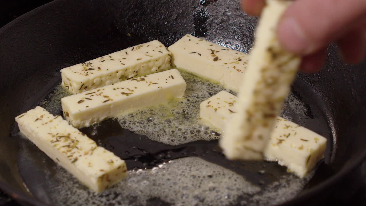 los dedos de queso de hierba halloumi se colocan en una sartén caliente para freír