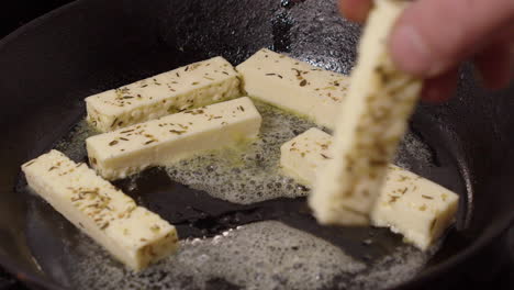 Halloumi-herb-cheese-fingers-are-placed-into-sizzling-hot-pan-to-fry