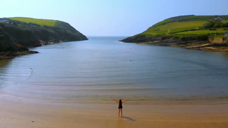 Woman-standing-on-the-beach-with-her-hands-spread-4k