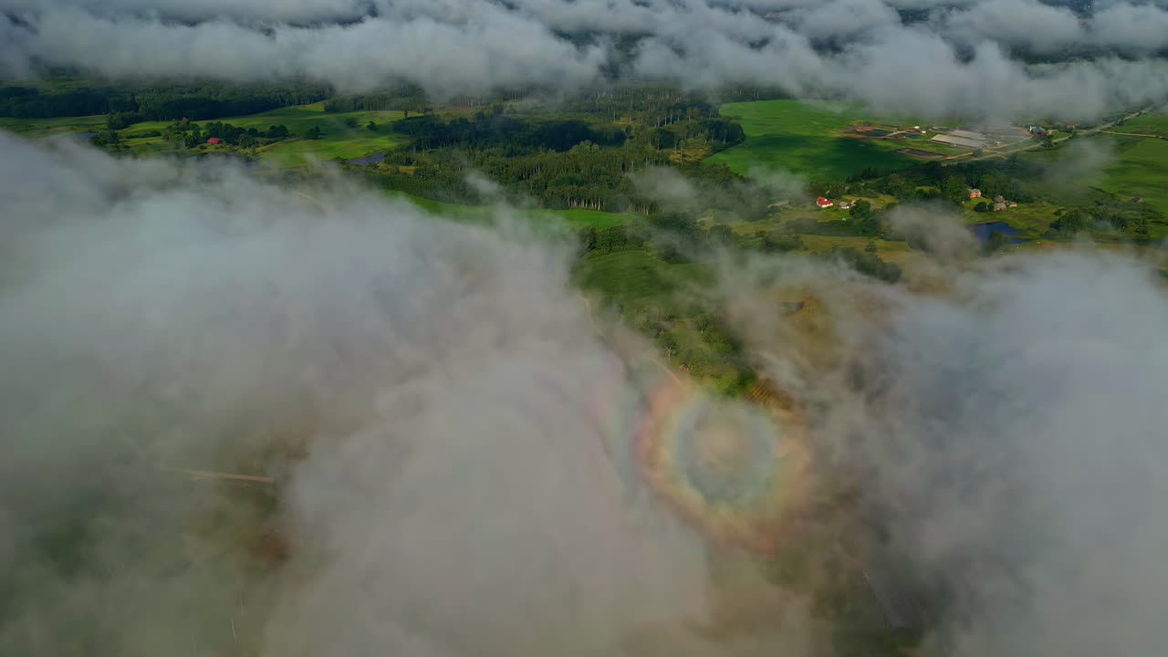 un paisaje de niebla envuelta, vegetación exuberante en las montañas, resaltado por una gloria visible - toma aérea de drone