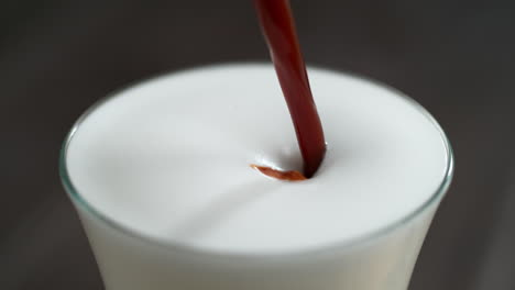 hacer capuchino o latte vertiendo café espresso para suavizar la leche espumosa en cámara lenta