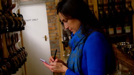 vista lateral de una mujer escribiendo en un bloc de notas en un supermercado 4k