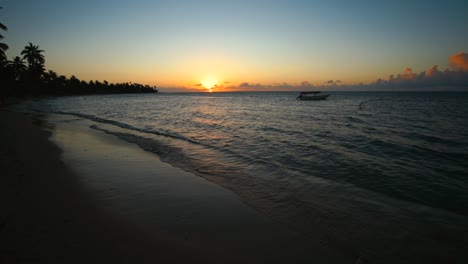 nice view of ocean,boat and sandy caribbean beach at sunrise,grand bahia principe beach at samana peninsula,dominican republic.