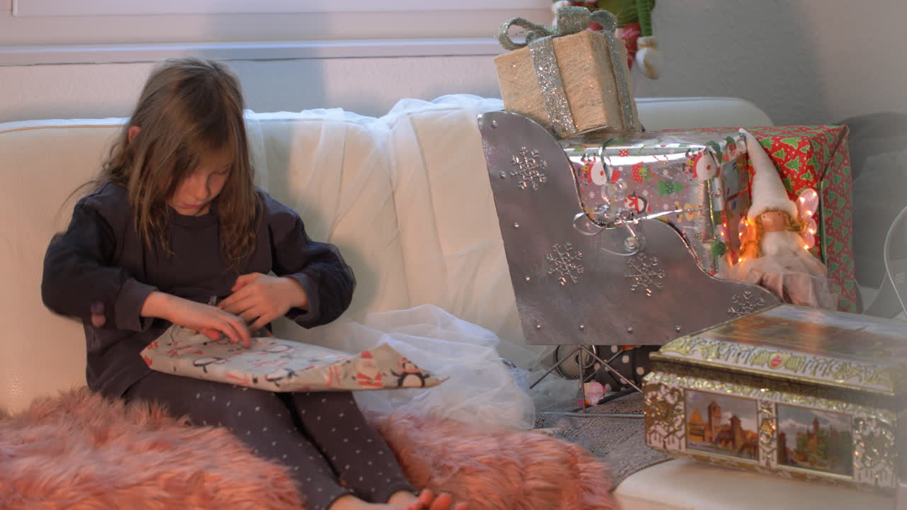 una niña muy adorable desenvuelve con entusiasmo el regalo de navidad