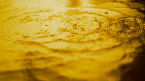 agua en movimiento lento gotas de lluvia cayendo sobre el agua sobre el suelo, hermosa superficie azul onda papel tapiz abstracto, patrón de círculo en el suelo, salpicaduras de gota de lluvia caendo y goteando en el suelo mojado