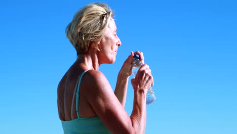 Fit senior woman pausing on her run to take a drink