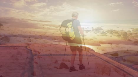 Happy-caucasian-senior-man-hiking-by-the-coast-over-fast-moving-clouds