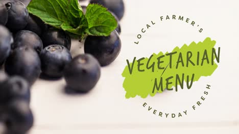 Animation-of-vegetarian-menu-text-in-green-over-fresh-organic-blueberries