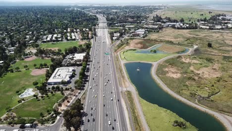 Vista-Aérea-De-Los-Suburbios-árboles-Densos-Casas-En-Los-Tejados-Pinos-Coches-Autopista-101-Marsh-Campo-De-Golf-Mantener-El-Vuelo-Estacionario