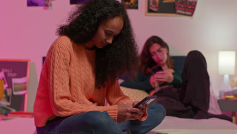 teenage girls using smartphones in a bedroom