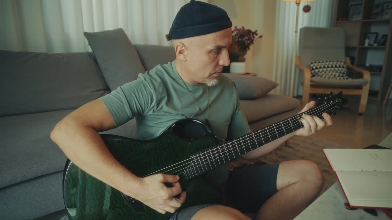 Uomo che suona una chitarra acustica verde nel suo salotto