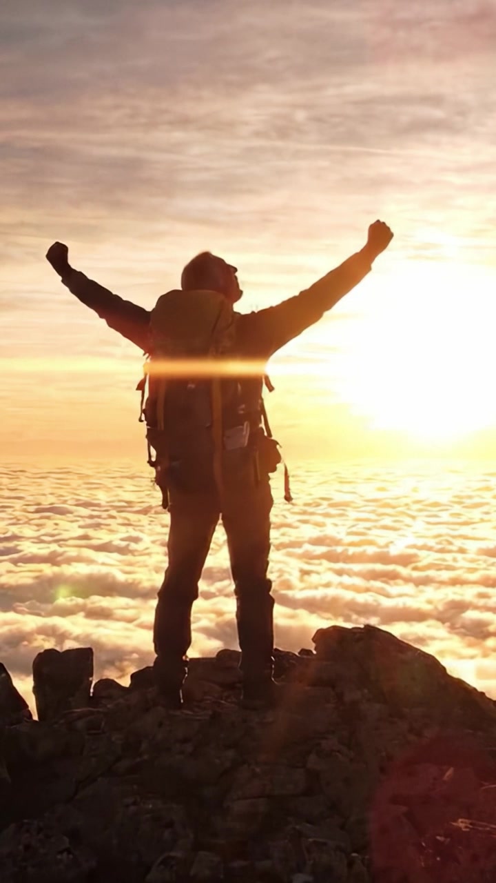 Escursionista trionfante che celebra l'alba da una maestosa cima di montagna sopra le nuvole con un orizzonte infuocato, rappresentando avventura e realizzazione.