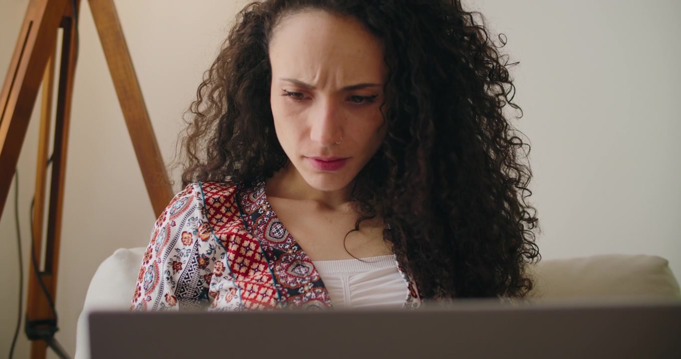 Soustředěná mladá žena pracující na notebooku doma