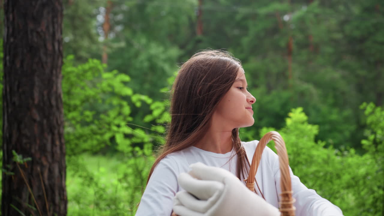 푸르른 숲속에서 피크닉 바구니를 들고 행복하게 미소짓는 쾌활한 어린 소녀의 모습이에요. 평화로운 야외 분위기를 즐기며 기쁨, 평온함, 그리고 자연과의 교감을 느끼고 있어요.